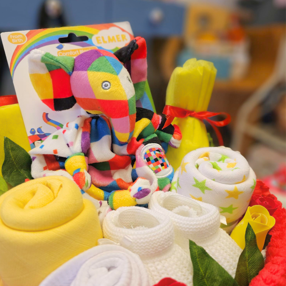 Bright nappy cake. Created using nappies and a soft baby blanket (and filled with lots of goodies), the gorgeous cake is then hand-wrapped in cello