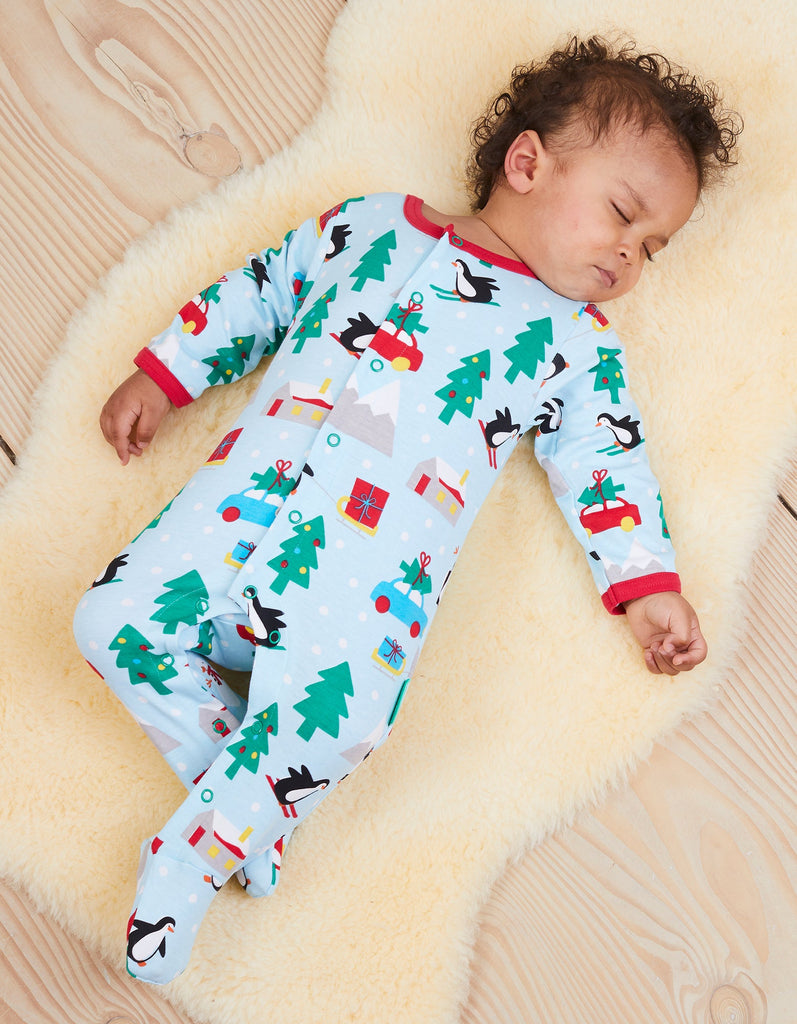 This fabulous Toby Tiger Organic Penguin Christmas Print Sleepsuit in pale blue features sledging penguins and a sweet winter scene with a bold red trim. Sold by Say It Baby Gifts